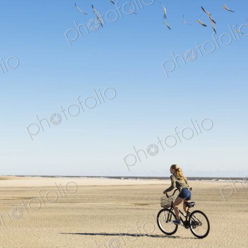 A teenage girl cycling on sand towards a flock of seagulls, St. Simon's Island, Georgia A teenage girl cycling on sand towards a flock of seagulls, St. Simon's Island, Georgia