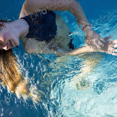 A teenage girl in a swimming pool, her long blond hair fanning out in the water. A teenage girl in a swimming pool, her long blond hair fanning out in the water.