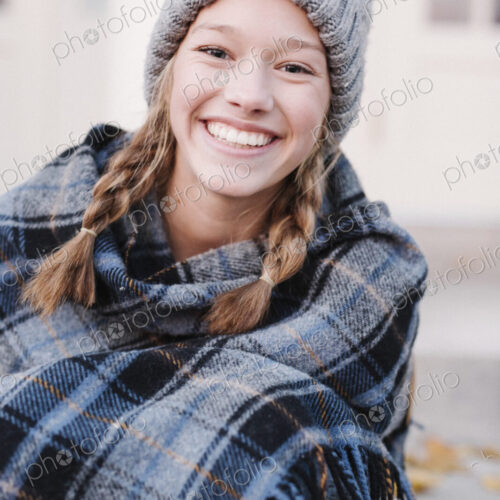 A teenage girl in a tartan plaid shawl and woolly hat outdoors in the winter. A teenage girl in a tartan plaid shawl and woolly hat outdoors in the winter.