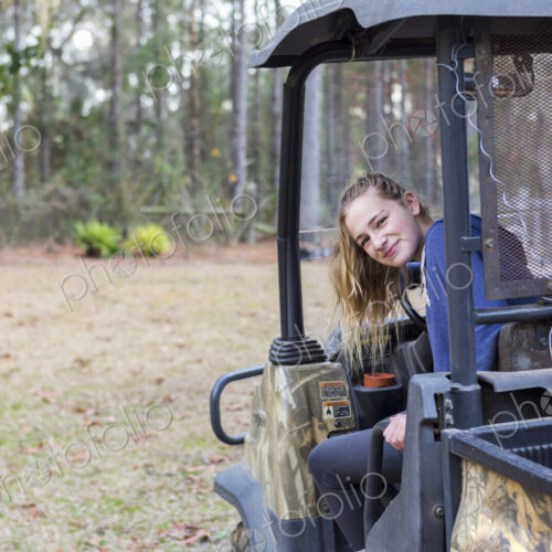 A teenage girl in an all terrain vehicle, a buggy, looking out.