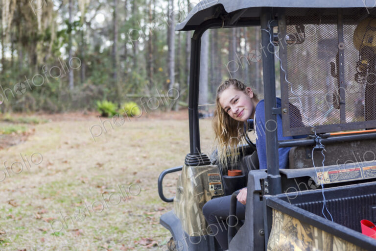 A teenage girl in an all terrain vehicle, a buggy, looking out.