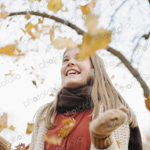A teenage girl outdoors throwing autumn leaves into the air. A teenage girl outdoors throwing autumn leaves into the air.