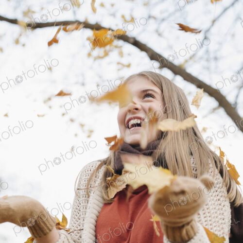 A teenage girl outdoors throwing autumn leaves into the air. A teenage girl outdoors throwing autumn leaves into the air.