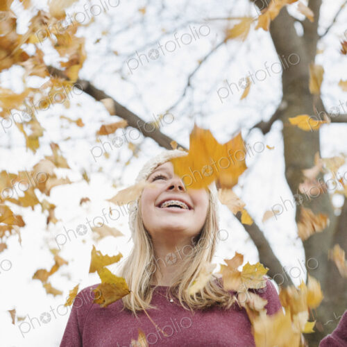 A teenage girl outdoors throwing autumn leaves into the air. A teenage girl outdoors throwing autumn leaves into the air.
