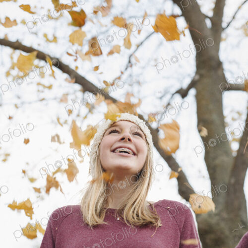 A teenage girl outdoors throwing autumn leaves into the air. A teenage girl outdoors throwing autumn leaves into the air.