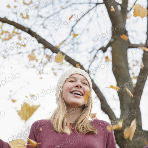A teenage girl outdoors throwing autumn leaves into the air. A teenage girl outdoors throwing autumn leaves into the air.