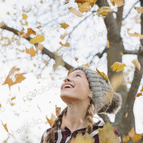 A teenage girl outdoors throwing autumn leaves into the air. A teenage girl outdoors throwing autumn leaves into the air.