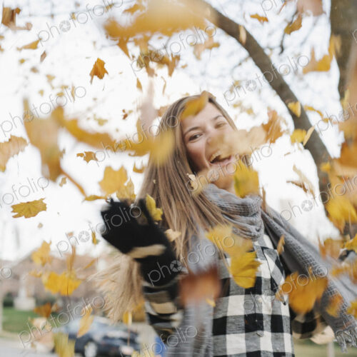 A teenage girl outdoors throwing autumn leaves into the air. A teenage girl outdoors throwing autumn leaves into the air.