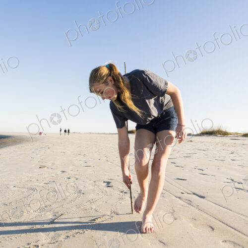 A teenage girl playing in sand dunes, at the beach A teenage girl playing in sand dunes, at the beach