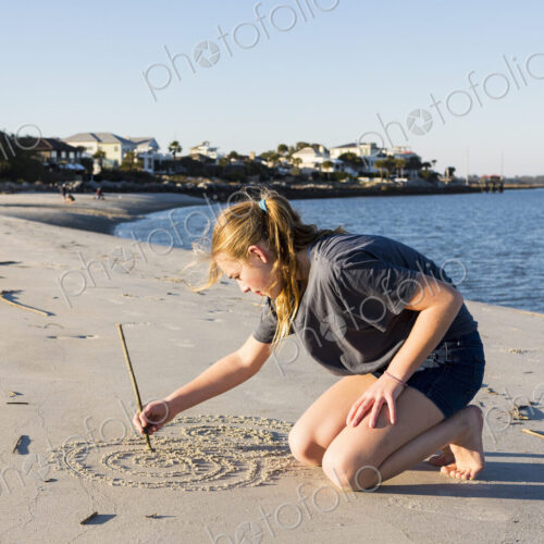 A teenage girl playing in sand dunes, at the beach A teenage girl playing in sand dunes, at the beach