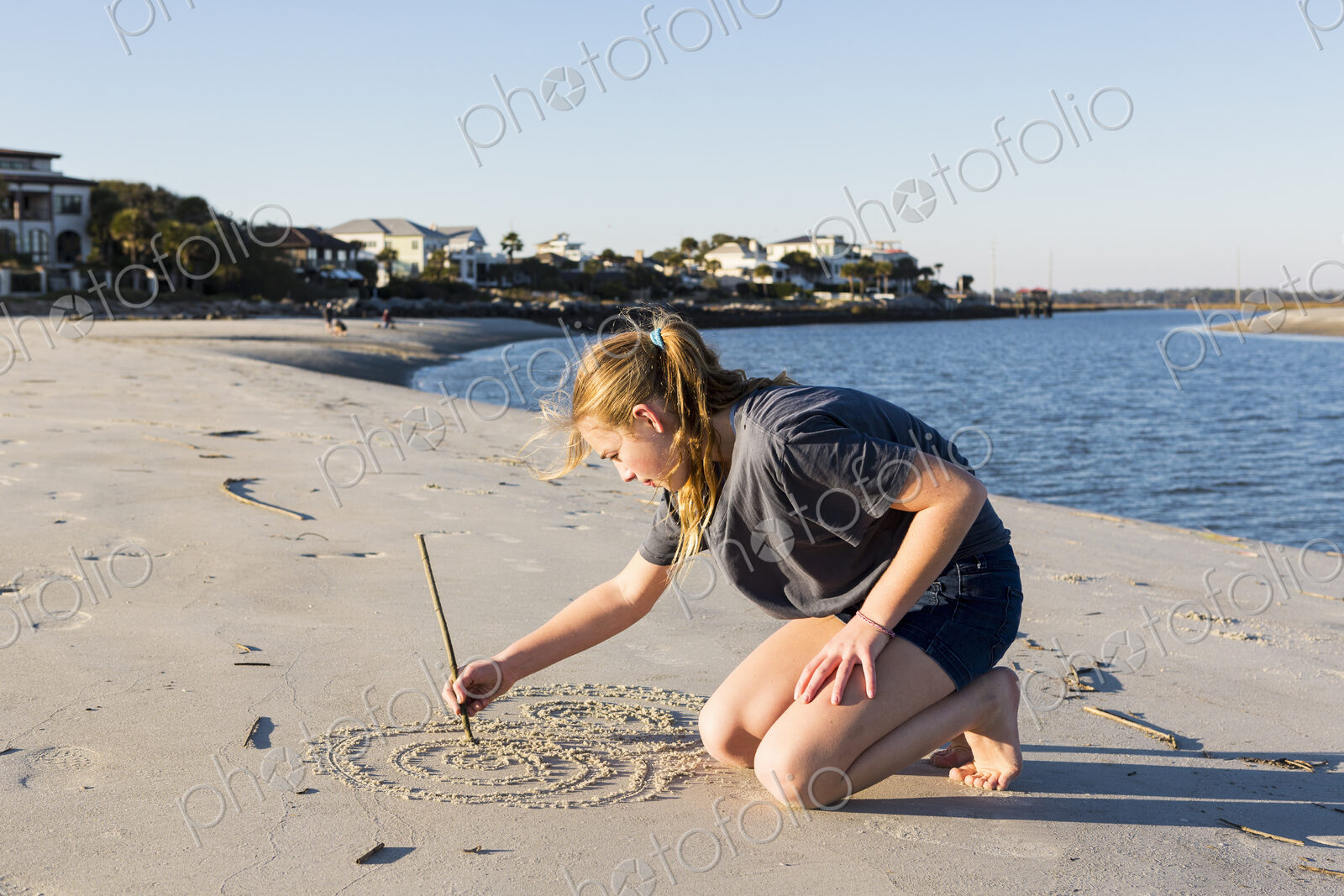A teenage girl playing in sand dunes, at the beach
