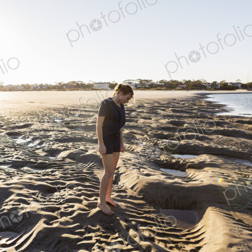 A teenage girl playing in sand dunes, at the beach A teenage girl playing in sand dunes, at the beach