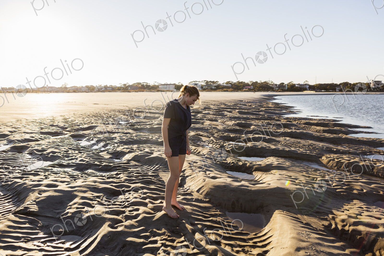 A teenage girl playing in sand dunes, at the beach