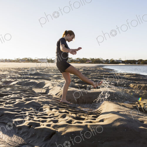 A teenage girl playing in sand dunes, at the beach A teenage girl playing in sand dunes, at the beach
