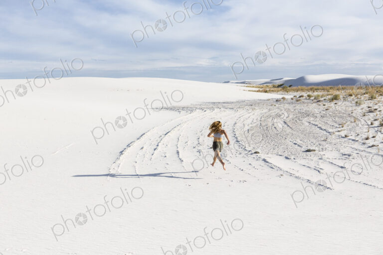 A teenage girl running in the sand, White Sands Nat'l Monument, NM