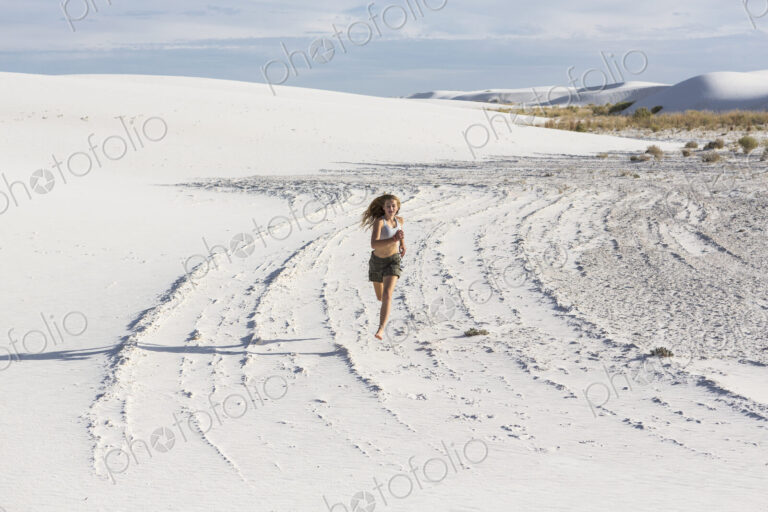 A teenage girl running in the sand, White Sands Nat'l Monument, NM