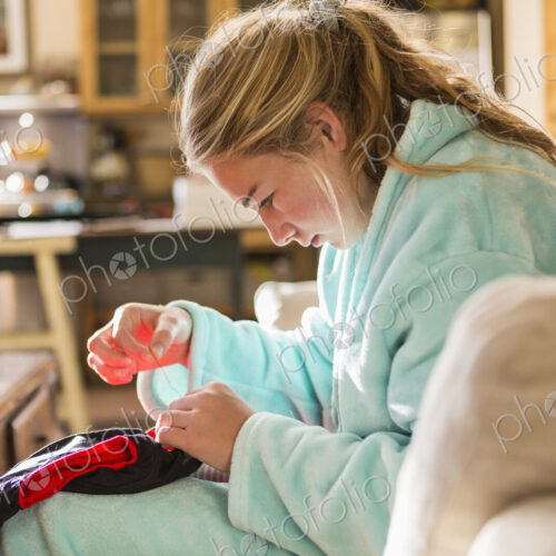 A teenage girl sewing a shirt sitting in her bathrobe. A teenage girl sewing a shirt sitting in her bathrobe.
