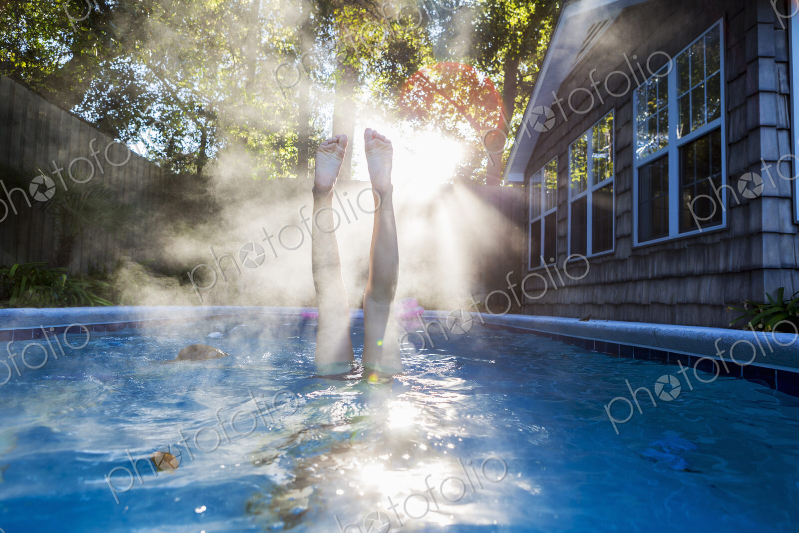 A teenage girl swimming in a pool, diving into warm water, steam rising.