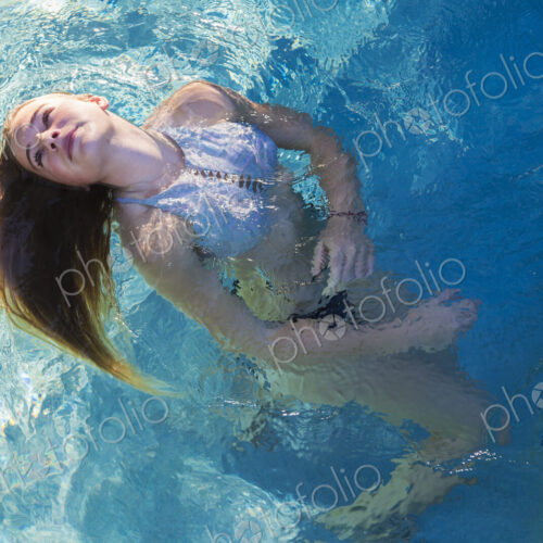 A teenage girl swimming in a pool, floating head back hair spread on the water. A teenage girl swimming in a pool, floating head back hair spread on the water.