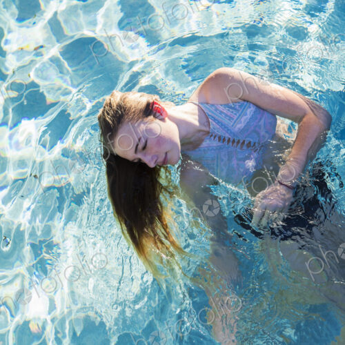 A teenage girl swimming in a pool, head back hair floating in the water. A teenage girl swimming in a pool, head back hair floating in the water.