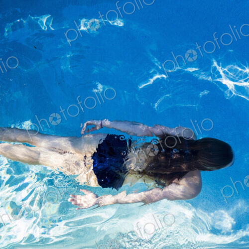 A teenage girl swimming in a pool, view from above. A teenage girl swimming in a pool, view from above.