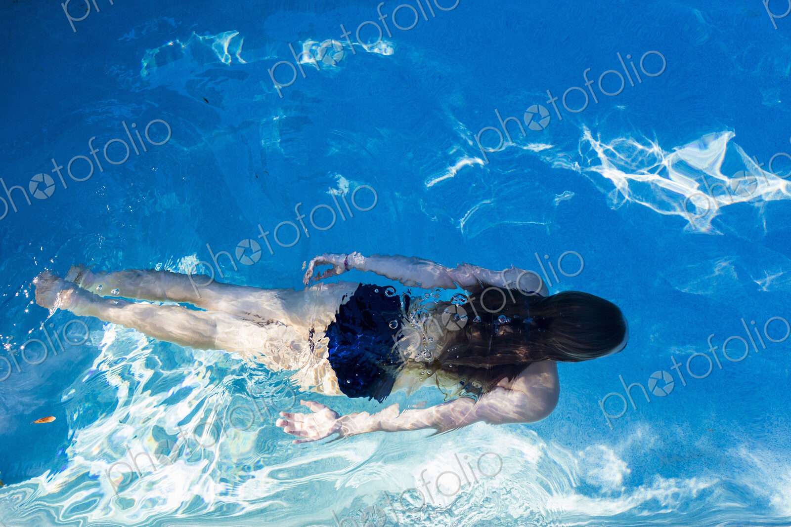 A teenage girl swimming in a pool, view from above.