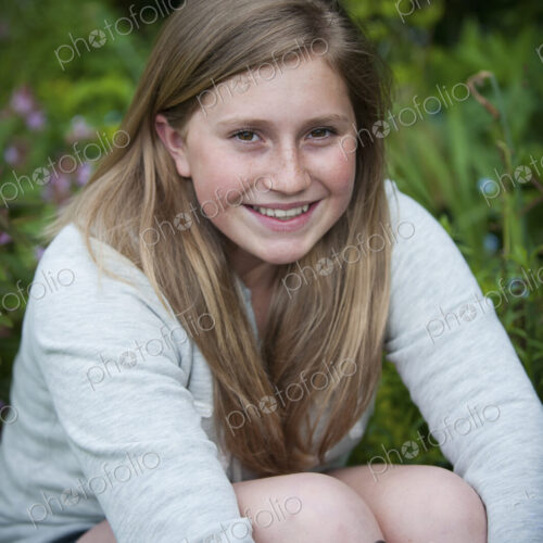 A teenage girl with brunette hair sitting in a garden. A teenage girl with brunette hair sitting in a garden.