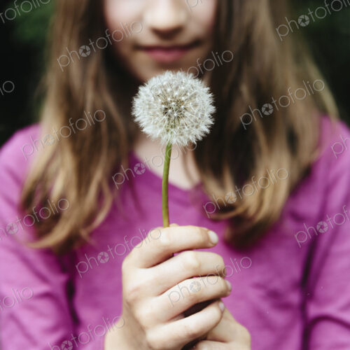 A ten year old girl holding a dandelion clock seedhead on a long stem. A ten year old girl holding a dandelion clock seedhead on a long stem.