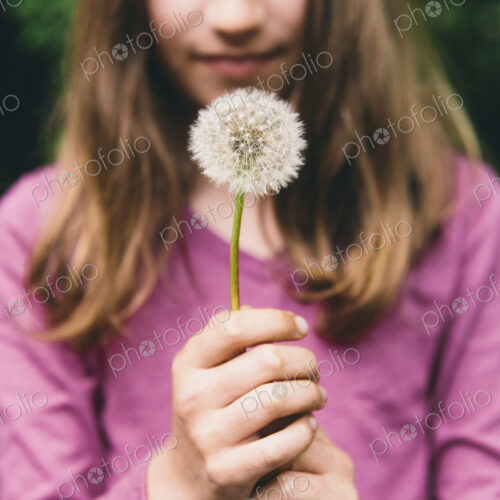 A ten year old girl holding a dandelion clock seedhead on a long stem. A ten year old girl holding a dandelion clock seedhead on a long stem.