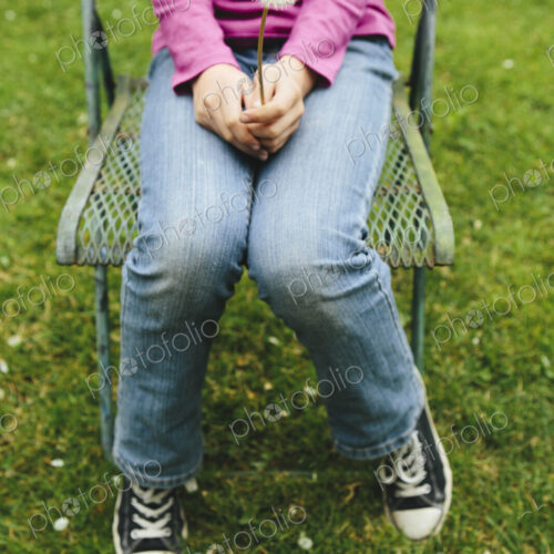 A ten year old girl sitting in chair on lush, green grass, holding a dandelion clock… A ten year old girl sitting in chair on lush, green grass, holding a dandelion clock…