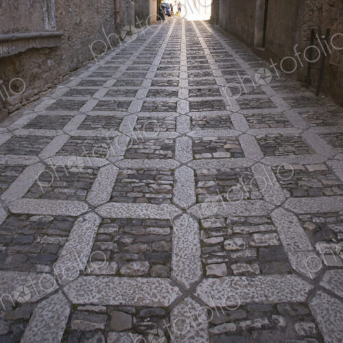 A textured cobblestone alley in the mountain village of Erice in Sicily.