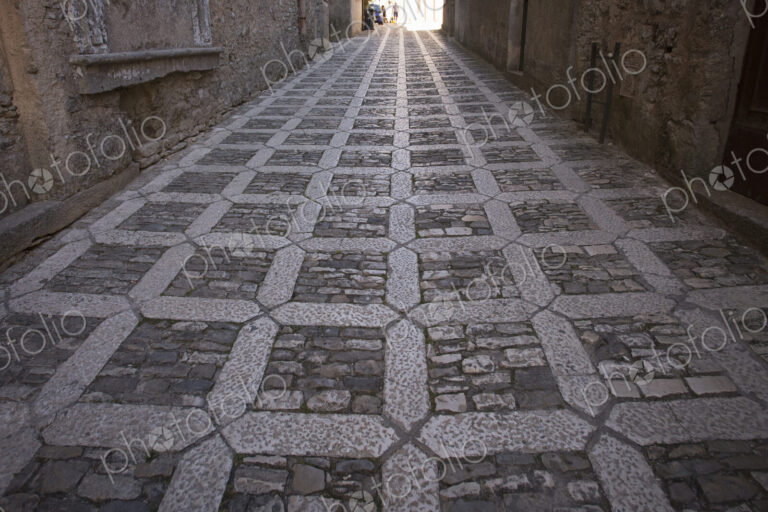 A textured cobblestone alley in the mountain village of Erice in Sicily.