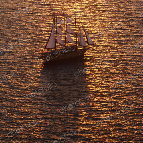 A three-masted sailing ship with full sail on the Aegean Sea at sunset. A three-masted sailing ship with full sail on the Aegean Sea at sunset.