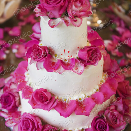 A three tiered wedding cake, covered in white frosting and decorated with pink rose… A three tiered wedding cake, covered in white frosting and decorated with pink rose…