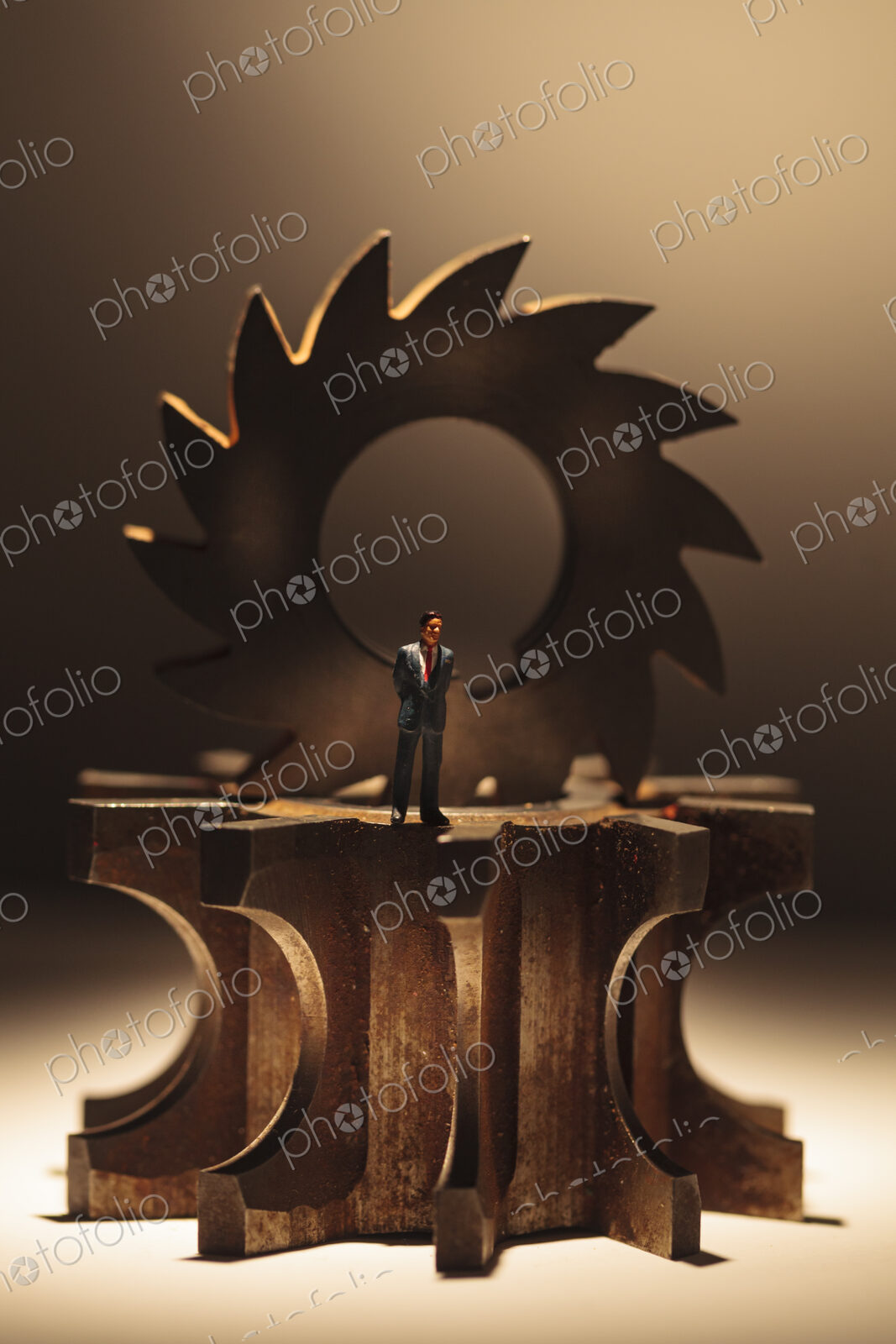 A toy model of a Businessman standing by three stacked cog wheels with different gearing.