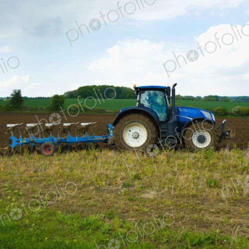 A tractor harrowing, ploughing in the stubble in a field. A tractor harrowing, ploughing in the stubble in a field.