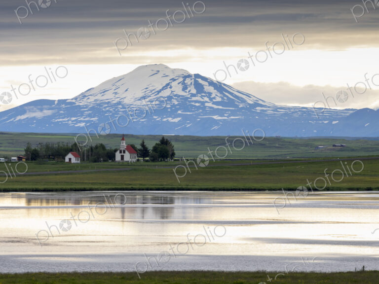 A traditional church on a lake shore in a mountain landscape.