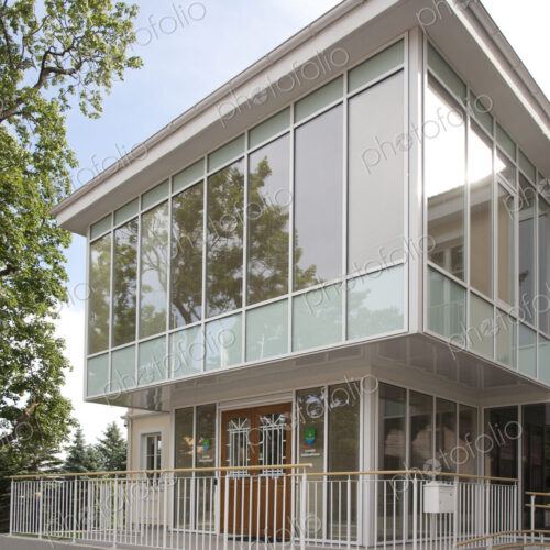 A traditional house with a modern glass extension, two storeys, with glass walls.