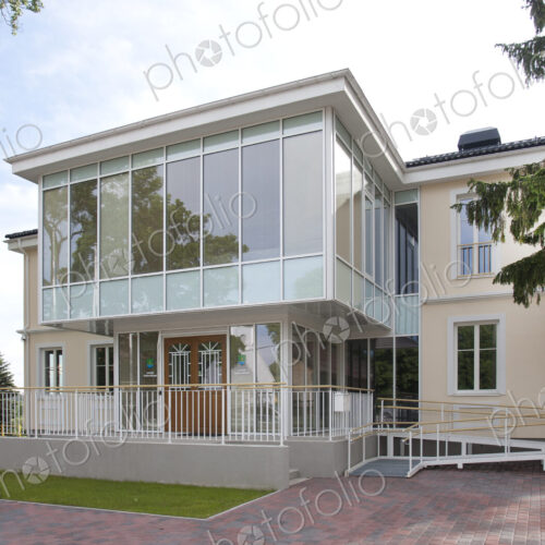 A traditional house with a modern glass extension, two storeys, with glass walls.