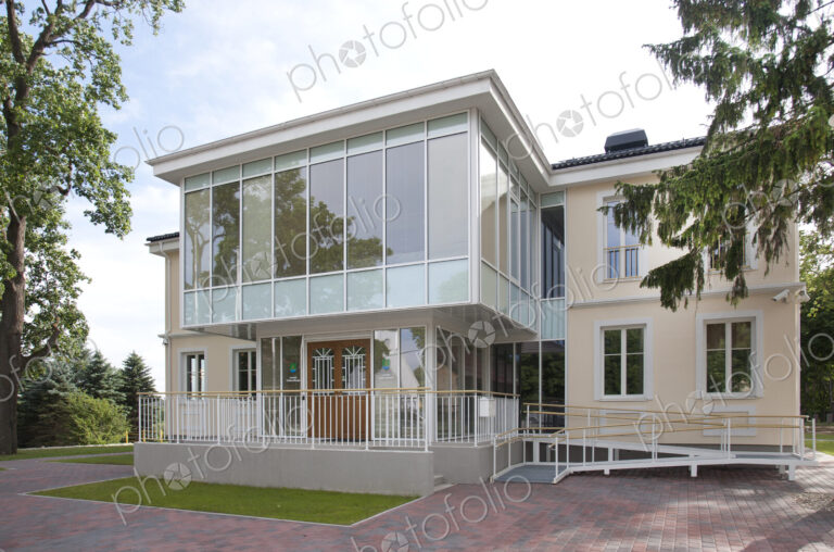 A traditional house with a modern glass extension, two storeys, with glass walls.
