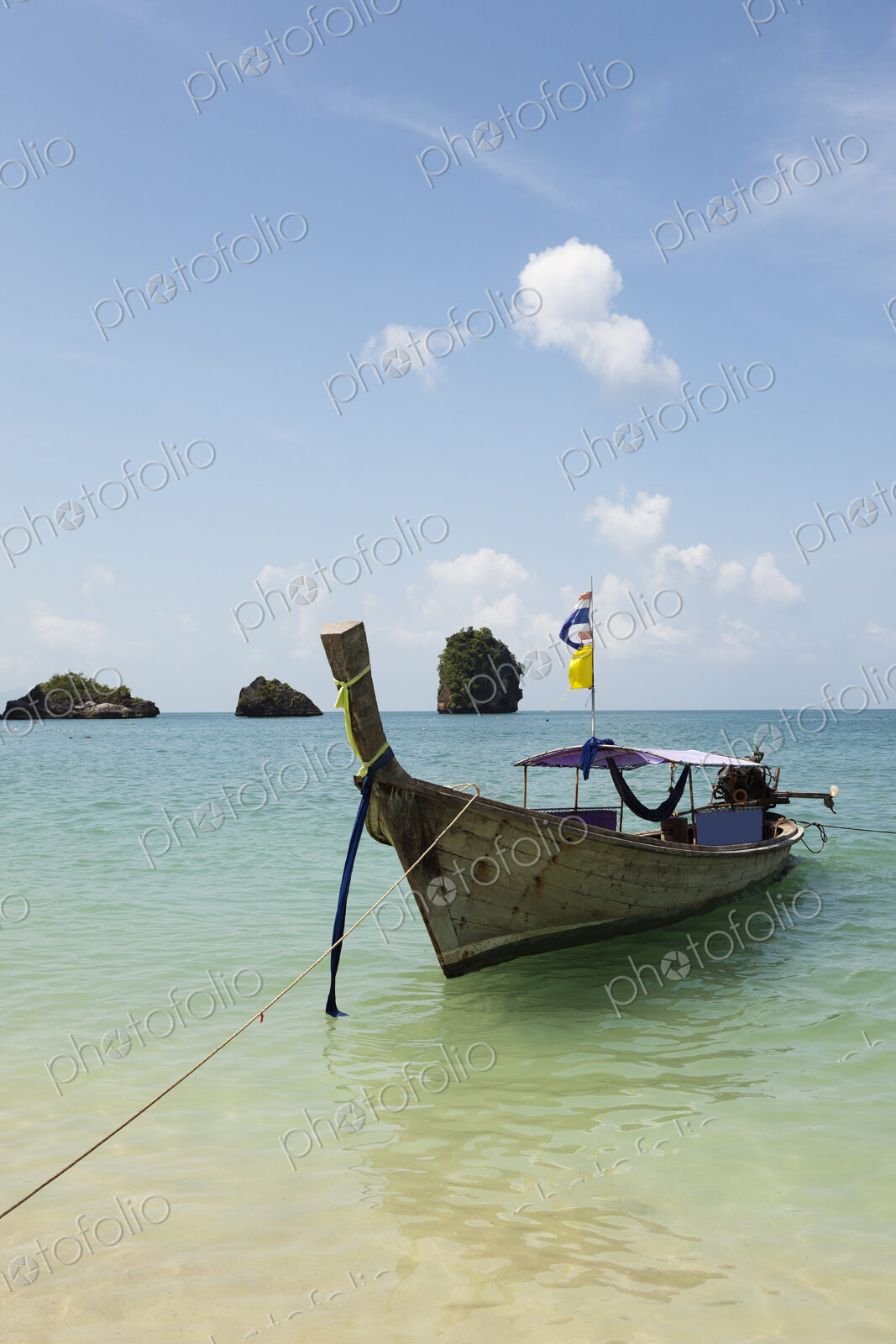 A traditional long tail boat moored in shallow water on Tham Phra Nang beach.