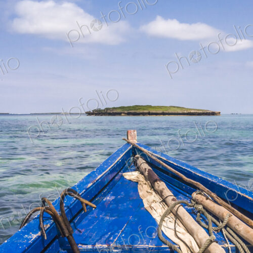 A traditional wooden boat with blue painted planks and a removable mast and furled sail.