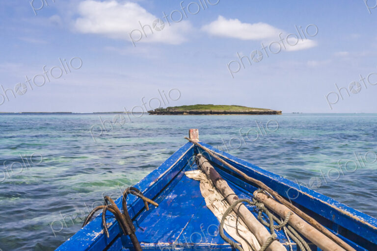 A traditional wooden boat with blue painted planks and a removable mast and furled sail.