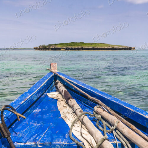 A traditional wooden boat with blue painted planks and a removable mast and furled…