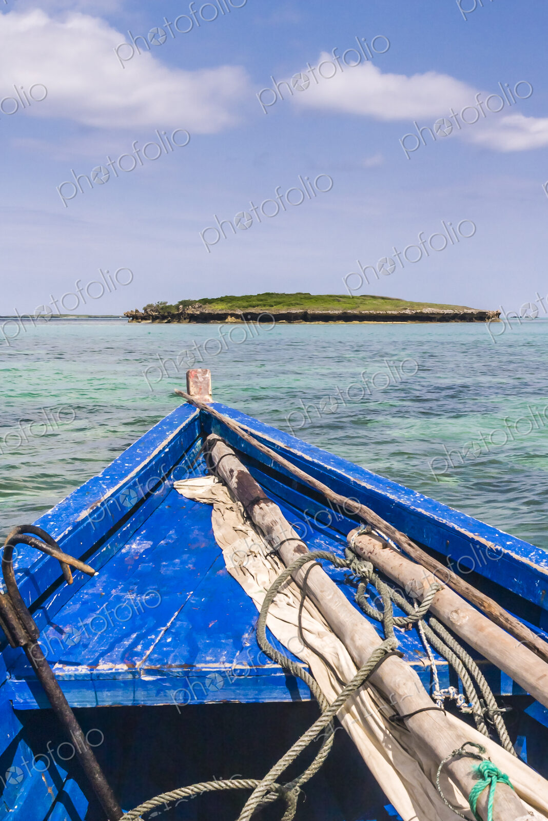A traditional wooden boat with blue painted planks and a removable mast and furled…