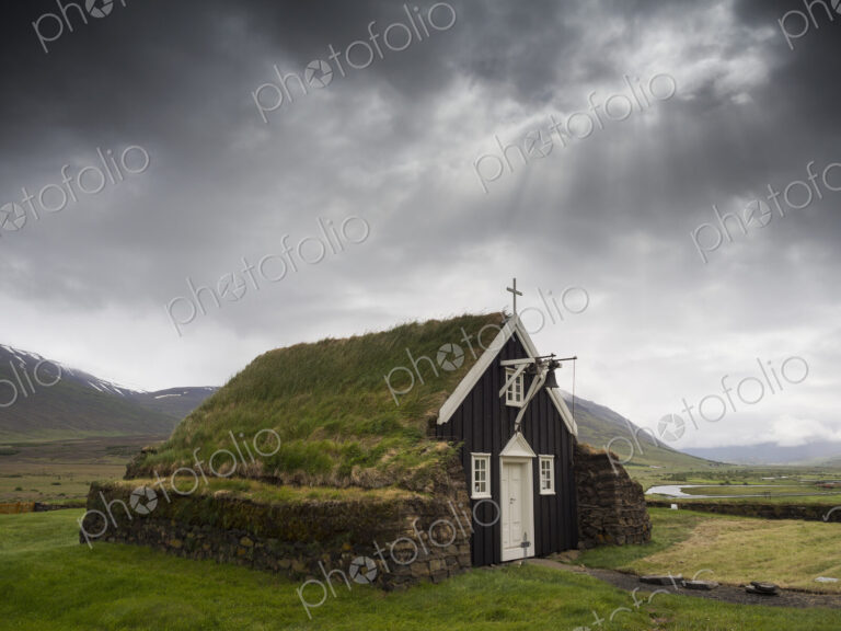 A traditional wooden church with turf roof, earth and grass material on the steep…