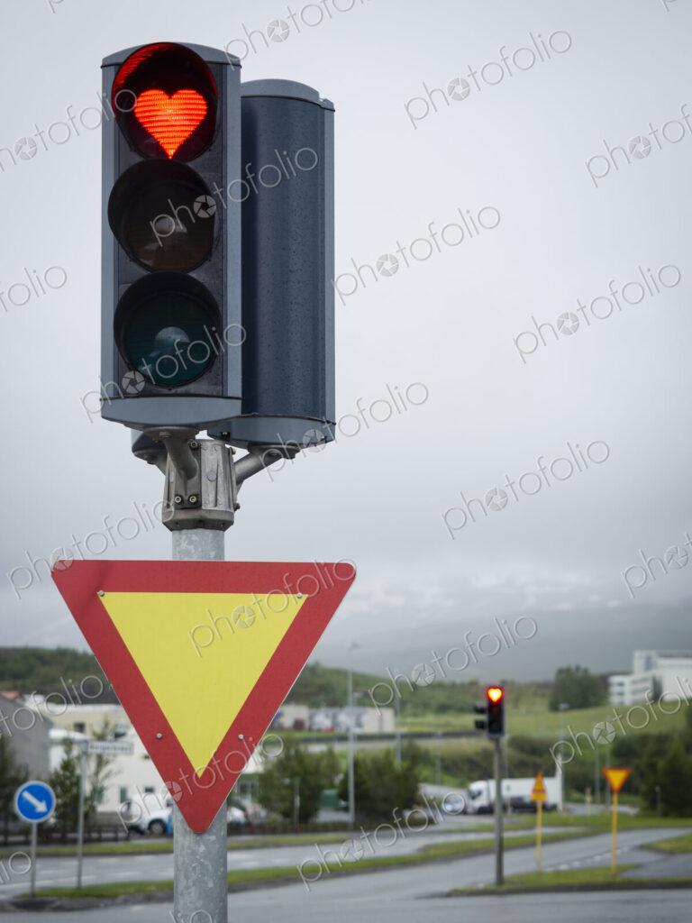 A traffic signal on the roadside, a heart shaped red light.