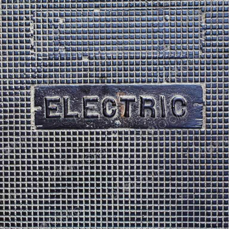 A utility cover made of metal, with the word Electric.