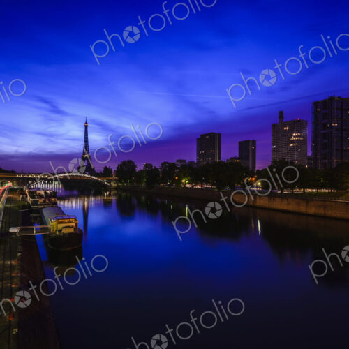 A view along the water of the River Seine at night, tall buildings on the river bank,… A view along the water of the River Seine at night, tall buildings on the river bank,…