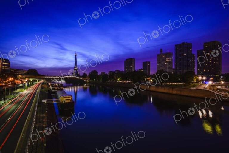 A view along the water of the River Seine at night, tall buildings on the river bank,…